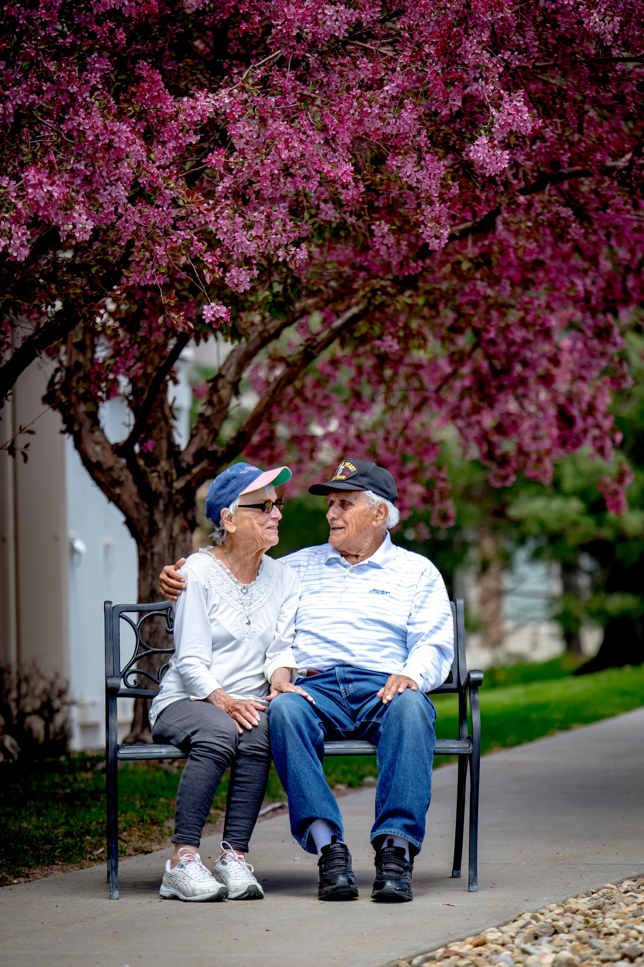 Two older adults seated beneath flowering trees at Golden Pond